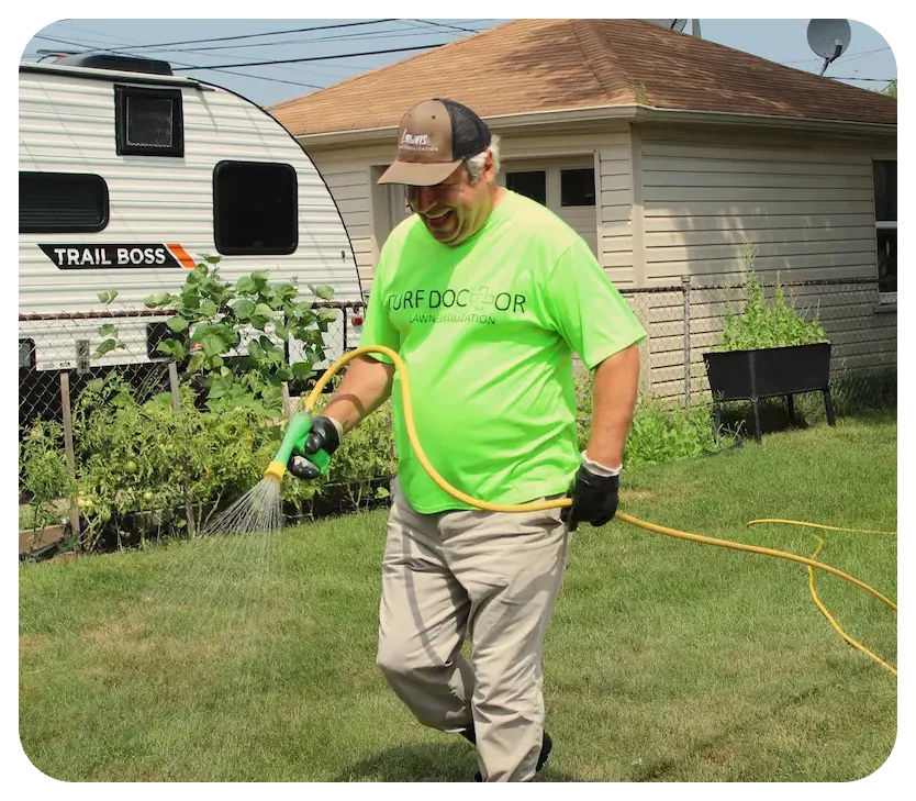 turf doctor technician smiling watering lawn